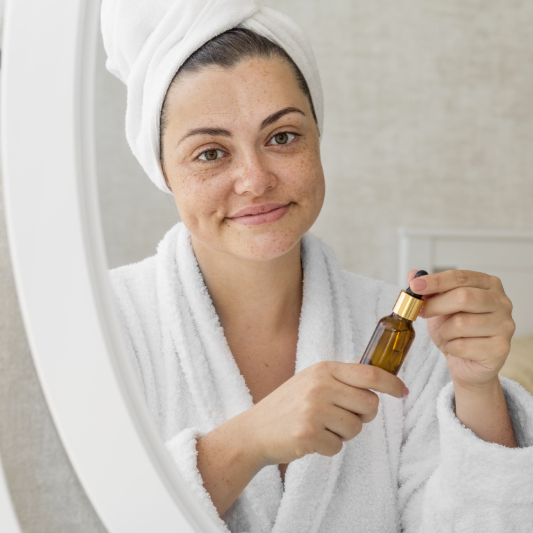 mujer con bata de baño y toallon en la cabeza usando aceites naturales para el rostro